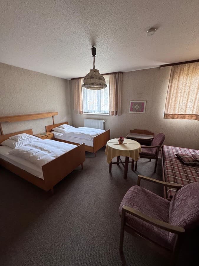 Gästezimmer mit zwei Einzelbetten und Sitzecke im Bestandszustand