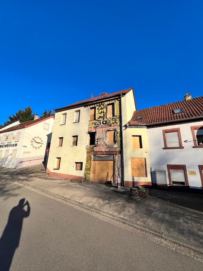Leerstehendes Wohnhaus mit verbretterten Fenstern und beschädigter Fassade