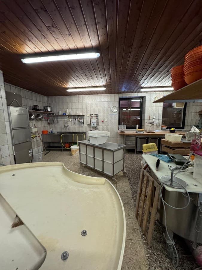 Gewerbliche Küche mit gefliesten Wänden, Edelstahlmöbeln und Holzdecke
